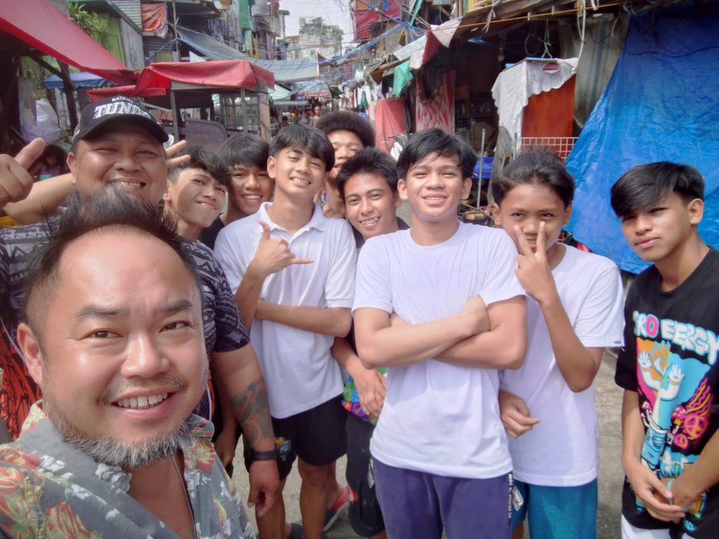 Group of youths smiling and posing for a photo in Tondo, Manila, highlighting community engagement and hope for educational support.