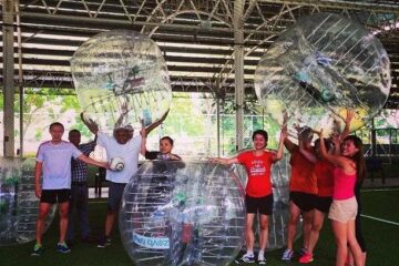 Group of people holding inflatable spheres in a sports facility.