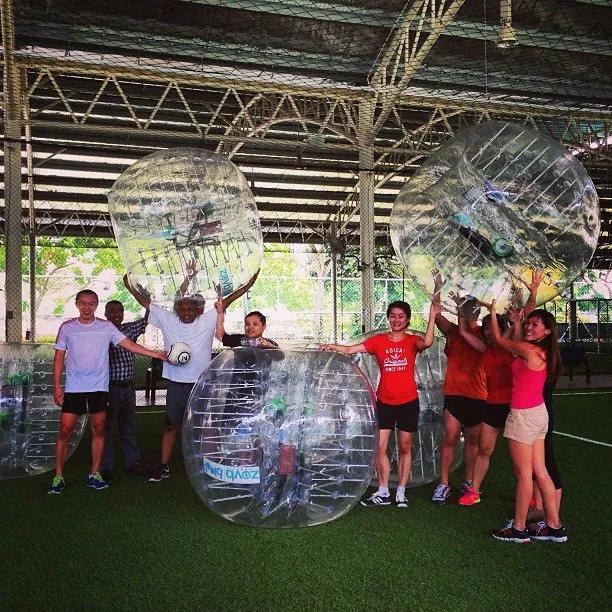 Group of people holding inflatable spheres in a sports facility.