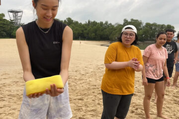 Young adults on a sandy beach participating in a water activity, smiling and interacting.