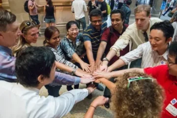 A group of diverse people joining hands in a collaborative gesture.