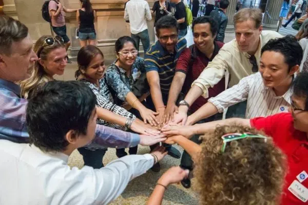 A group of diverse people joining hands in a collaborative gesture.
