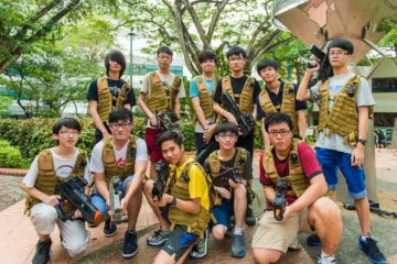 Group of young individuals in tactical vests holding toy guns outdoors.