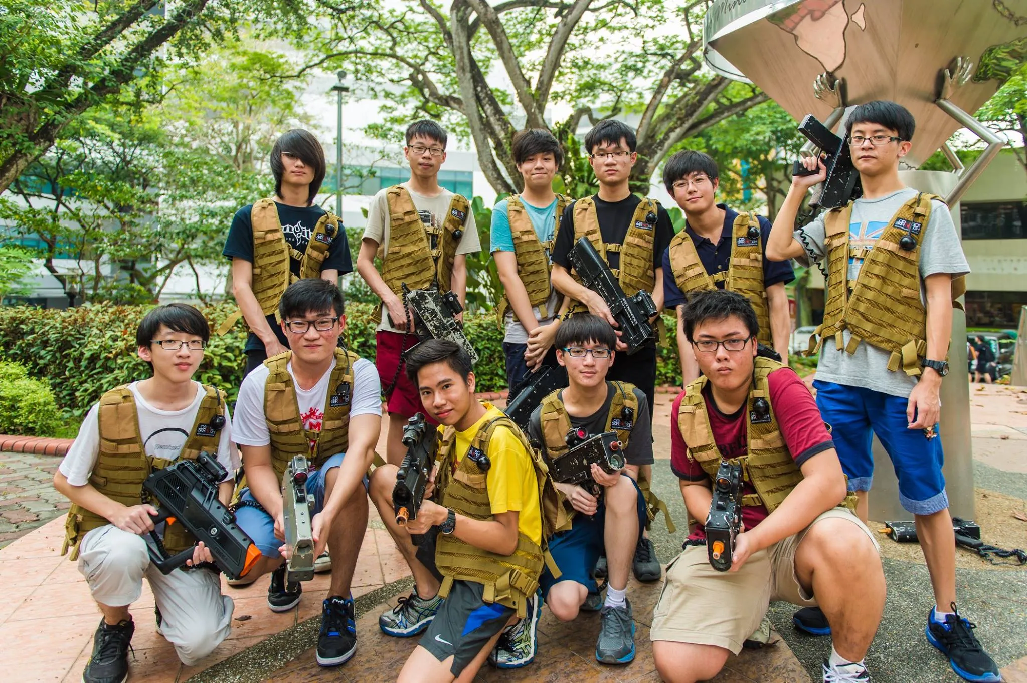 Group of young individuals in tactical vests holding toy guns outdoors.