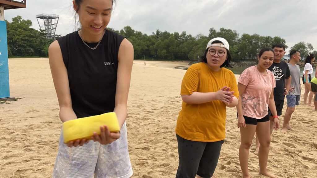 Young adults on a sandy beach participating in a water activity, smiling and interacting