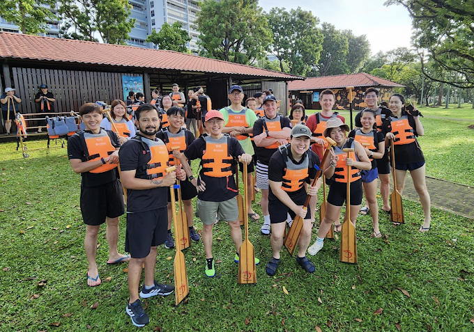 Group of people in life jackets holding paddles in a park setting