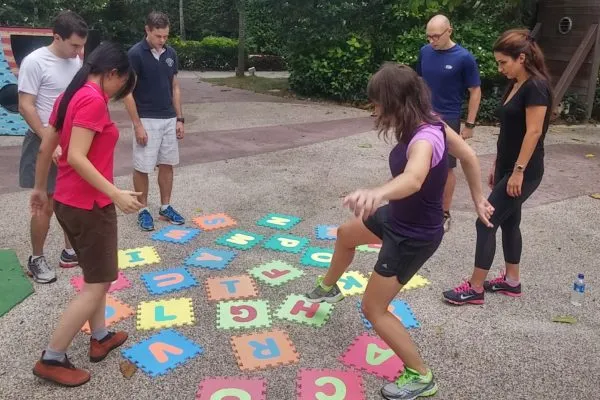 Adults playing a game on colorful foam letter tiles in a park