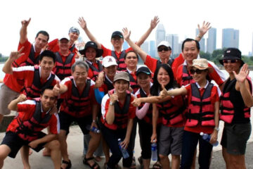 Group of people in red life vests posing with smiles in an urban setting.