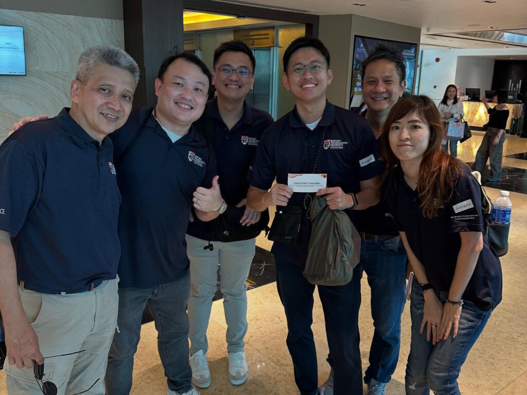 Six people in matching navy polo shirts posing happily indoors